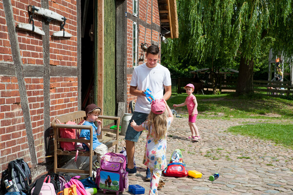 Ein Freiwilliger betreut Kinder bei einem Ausflug auf einen Bauerhof